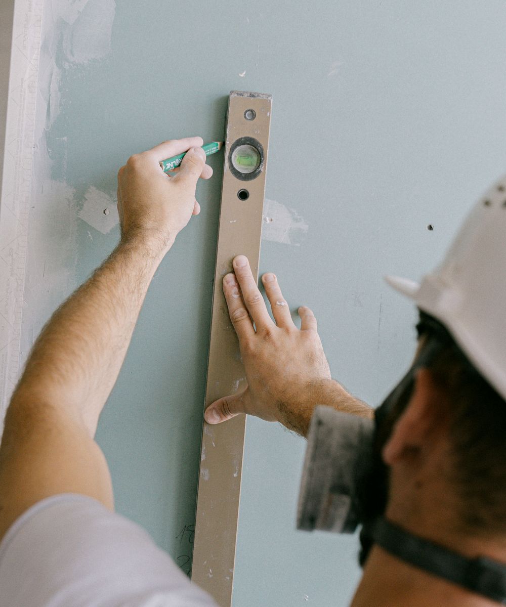 Compagnon QDK Bâtiment traçant un repère au niveau sur un chantier de rénovation